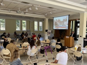 students sitting around tables in Lilly Gallery watch the German election on a screen