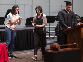 Sally Fredricks walks across stage with award plaque in hand smiling