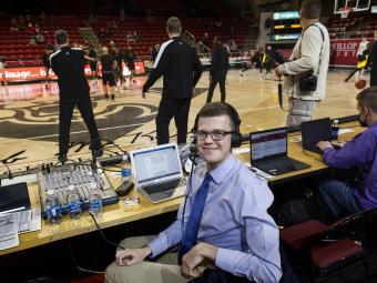 Sam Goldfarb at a basketball game with a headset and laptop on the sidelines