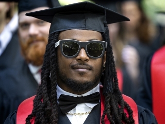 graduate in sunglasses and cap and gown