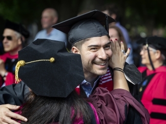 faculty member hugs graduate at commencement