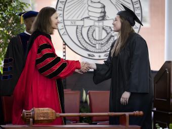 President Quillen shaking student's hand on stage at Class of 2022 Commencement