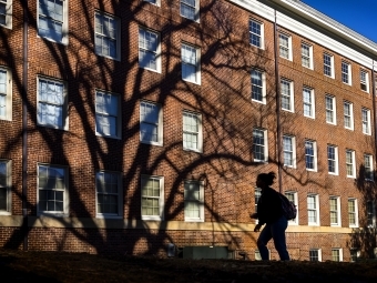 student walking on campus past dorms