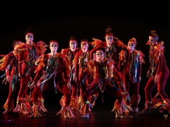 group of students in costumes and paper masks on stage