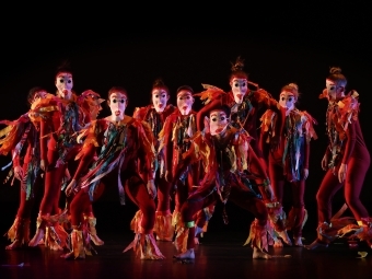 group of students in costumes and paper masks on stage 