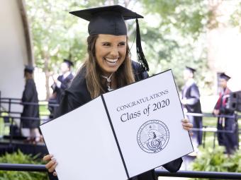Student holding diploma at Commencement for Class of 2022