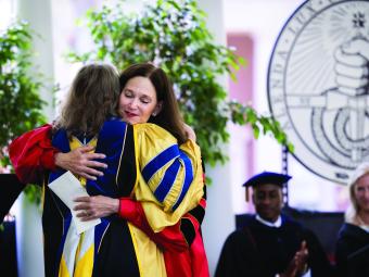 Carol Quillen hugs student on graduation stage 