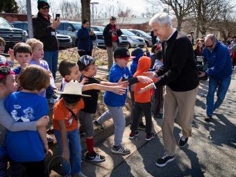 Coach McKillop shaking hands with line of elementary school children outside