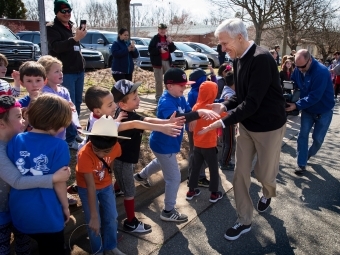 Coach McKillop shaking hands with line of elementary school children outside