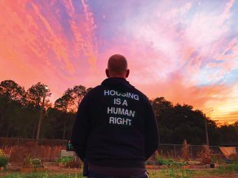 Photo of man facing away wearing sweatshirt that reads "Housing is a Human Right"