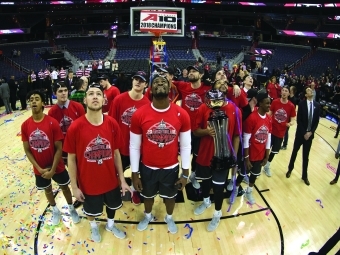 Group of Davidson students stand on a basketball court looking up 