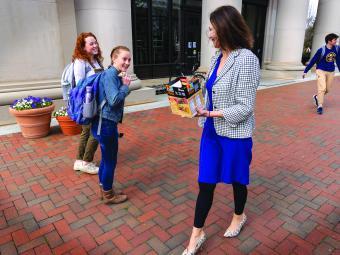 President Quillen handing a Kind bar to two students outside the library