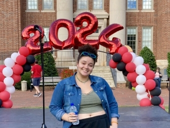 person smiling in front of 2026 balloon arch