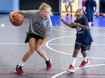 Kid playing basketball with current Davidson student