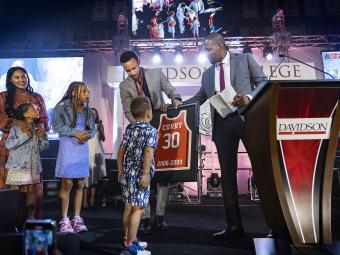 Chris Clunie presents Steph Curry and family a framed 30 jersey during the Steph for 3 Event