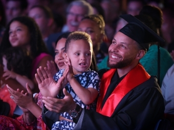 Stephan Curry applauds with his young son in lap