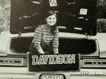a black and white photo of a young woman in front of car holding Davidson sign