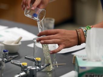 hands holding beakers in chemistry lab