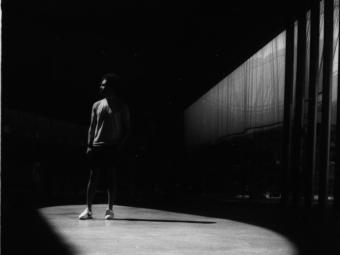 Photography by Claire Begalla ’24: black and white image of figure standing in the shadows