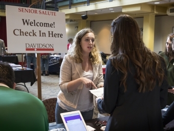 two women speaking in front of sign that says "senior salute"