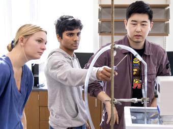 Three students gathered around a chemistry project