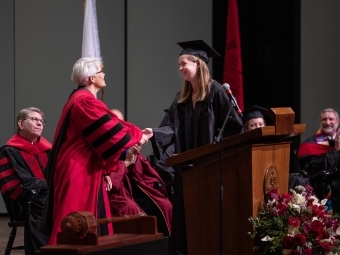 Student shaking hand of Shelley Rigger at Convocation