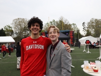 Two students smiling with football field in background