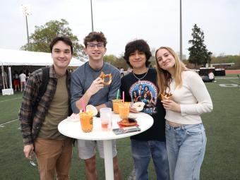 Group of four students smiling with boba teas around a high top table