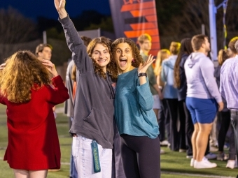 Two students smiling and waving at camera