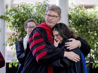 President Hicks embraces faculty member who wipes tears from her face