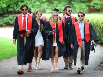Group of students in commencement regalia walking and smiling