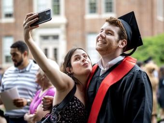 Student in cap and gown takes selfie