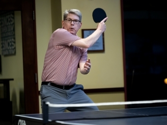 A white male hits a ping pong ball with a paddle