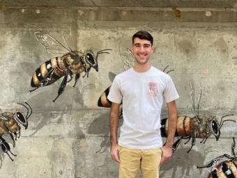 Student standing in front of bee mural