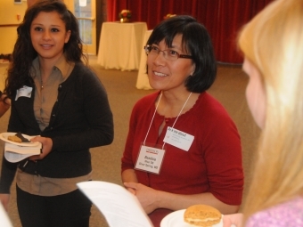 A woman speaks with two young students