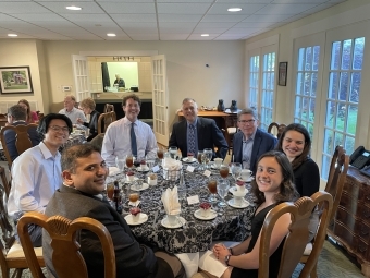 A group of students and adults sitting at a dining table and smiling