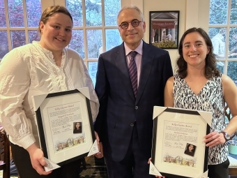 Two women standing with a male holding awards