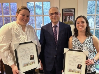 Two women standing with a male holding awards