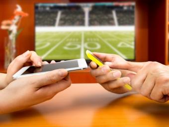 Two people on cell phones in front of football game
