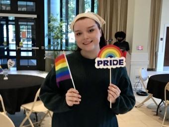 Student holds a rainbow flag and a sign that says "pride"