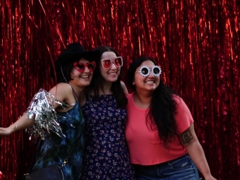 Young alumni smiling with glasses on and red back drop