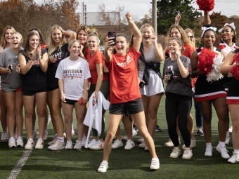 Athletes in Davidson uniforms cheering and taking a selfie