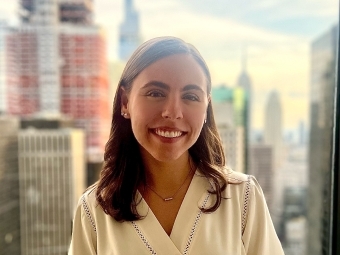 a young white woman smiles in front of a NYC skyline