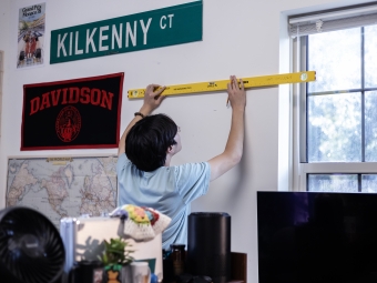 Student Hanging Artmate Art on Dorm Wall