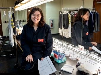 a young woman smiles while standing in a dressing room in front of a mirror