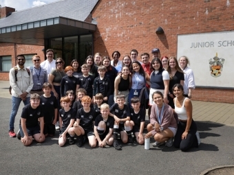 a group of college and middle school students standing in front of a brick building