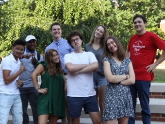 a group of students making silly faces while standing on stone steps outside