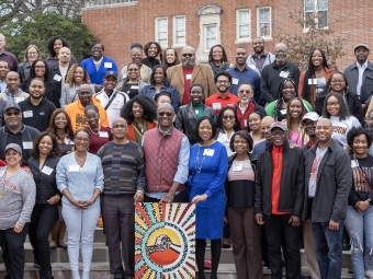 a group of Black folks standing on a set of stairs outdoors and smiling