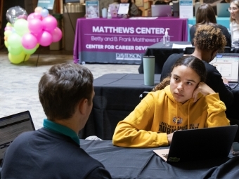 a student talks to an adult over a table with their laptops open