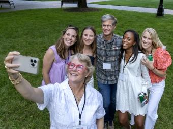 a group of alums pose to take a selfie together outside